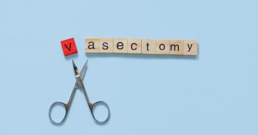 the word vasectomy made with wooden tiles on a blue background; V is red and scissors are under the word